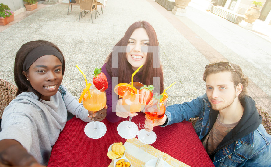 Three friends take a selfie make cheers celebrating multicultural friendship.