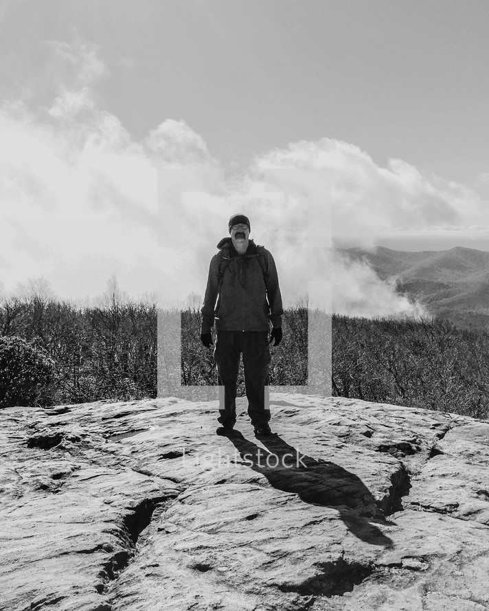 man standing on the top of a mountain casting a shadow 