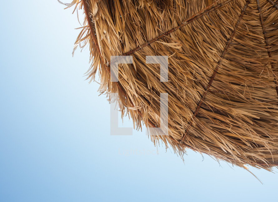 Thatched umbrella viewed from below with blue sky