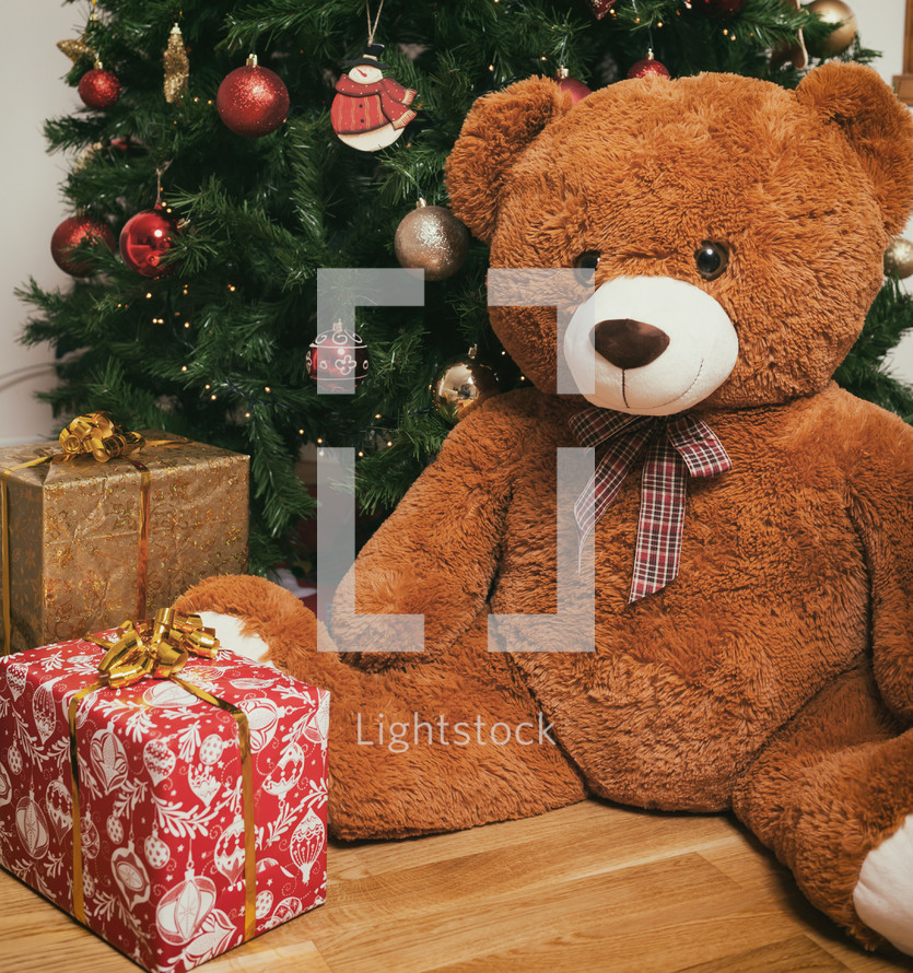 Teddy bear near christmas tree with gifts