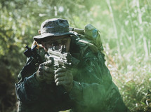 Airsoft military game player in camouflage uniform with armed assault rifle