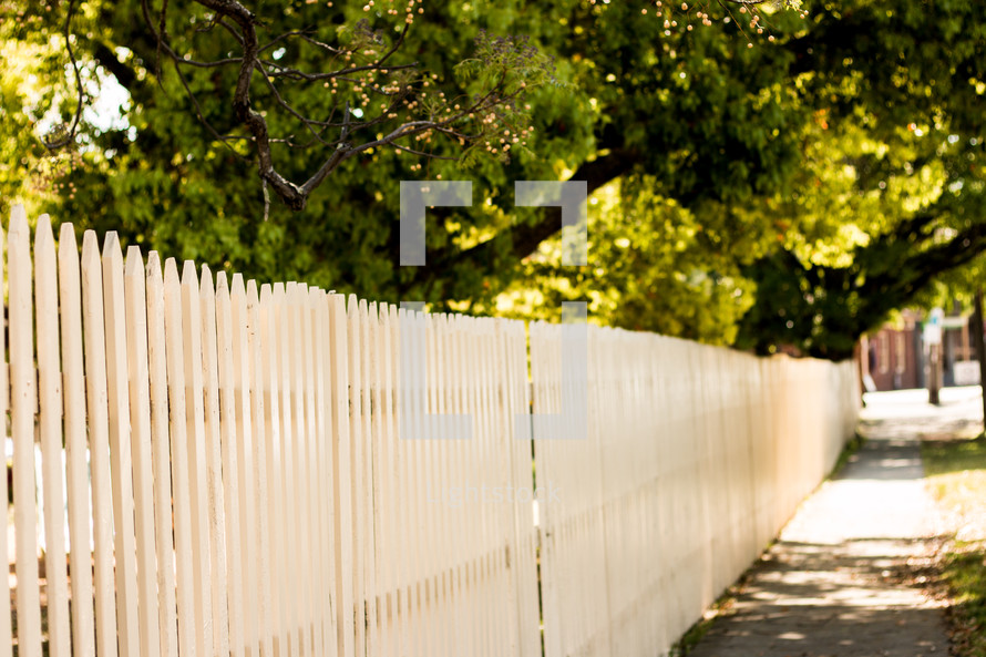 white picket fence and sidewalk in a neighborhood 