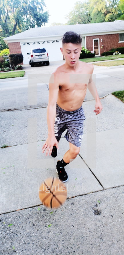 boy playing basketball in the driveway 