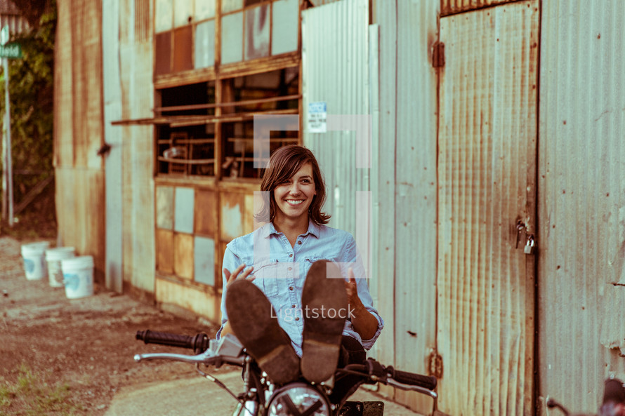 a woman sitting on a motorcycle resting her feet 