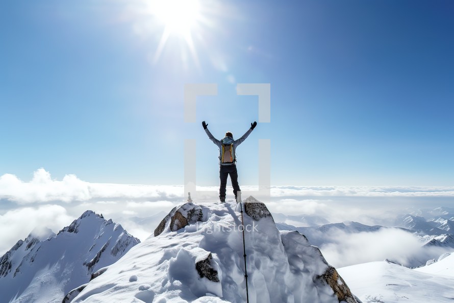 successful climber with arms raised standing on top of a snowy mountain