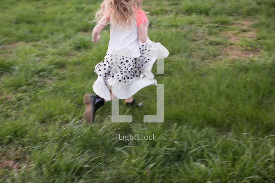 girl child running through green grass 