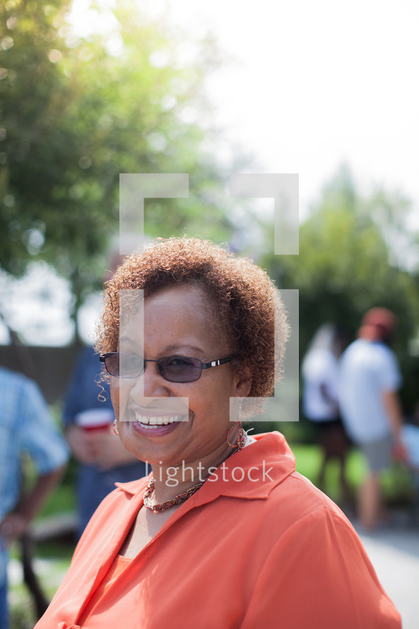 headshot of an African American woman and friends talking at a backyard summer party
