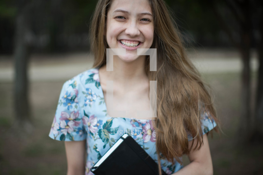 smiling young woman holding a Bible 