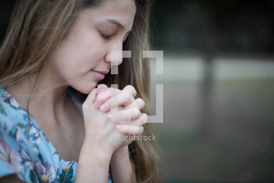 young woman with praying hands 