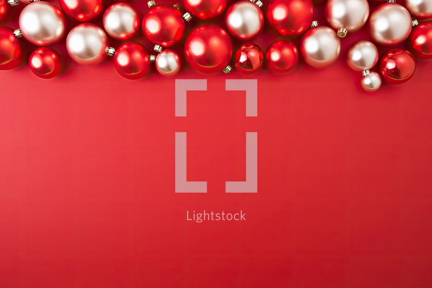 Christmas background with red and silver baubles on red background.