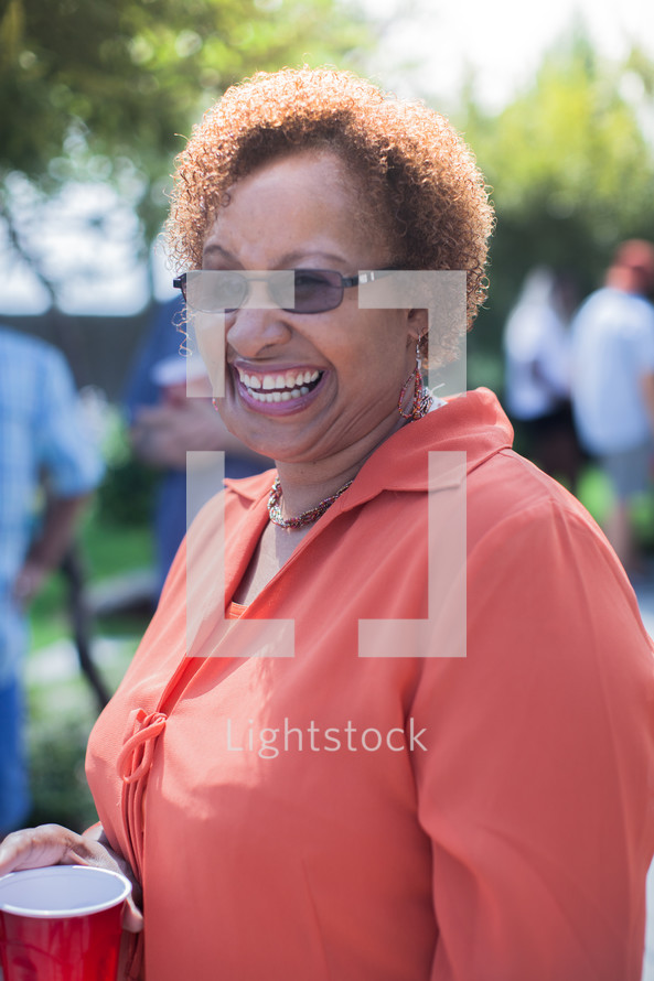 headshot of a woman and friends talking at a backyard summer party
