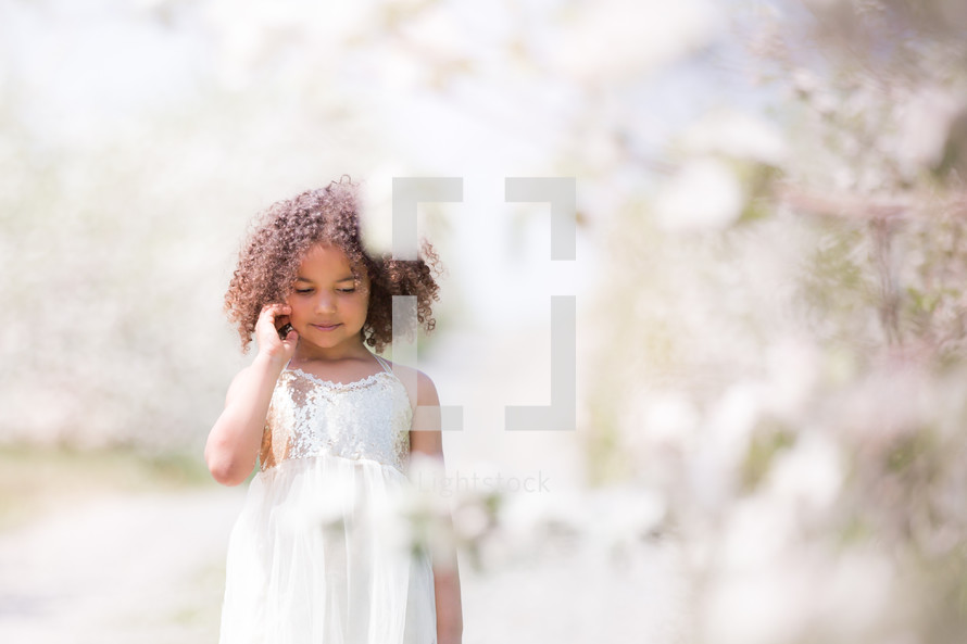 a little girl in a white dress standing in an orchard 