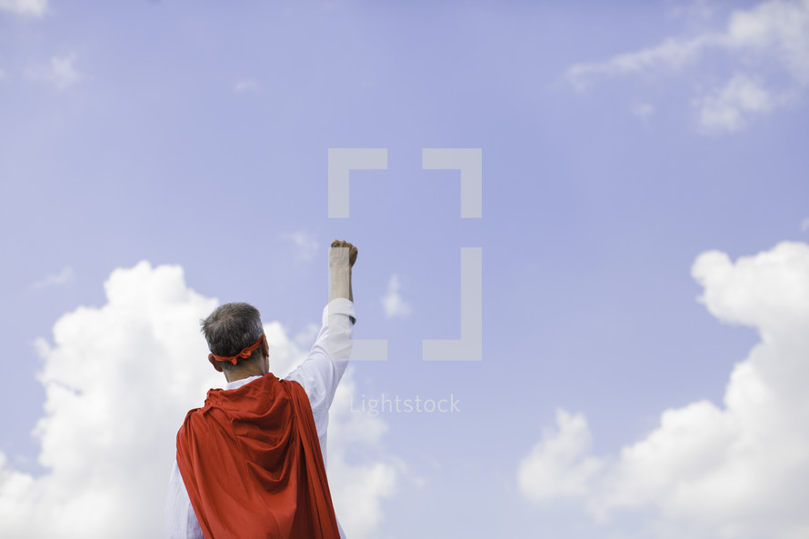 A Dad in a superhero cape with a raised fist 