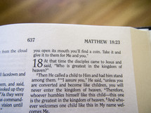 Bible open to Matthew 18:23.