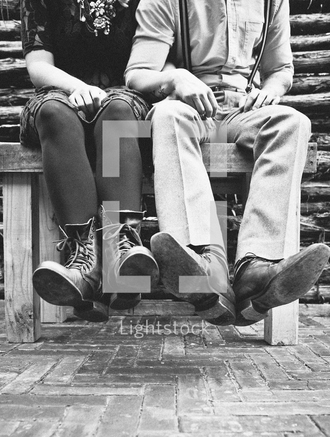 couples legs and feet dangling off a bench