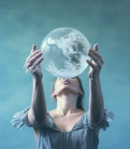 Young woman holding a glass ball with the planet earth in her hands