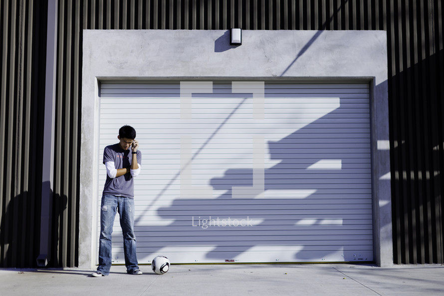 man standing with a soccer ball in front of a garage