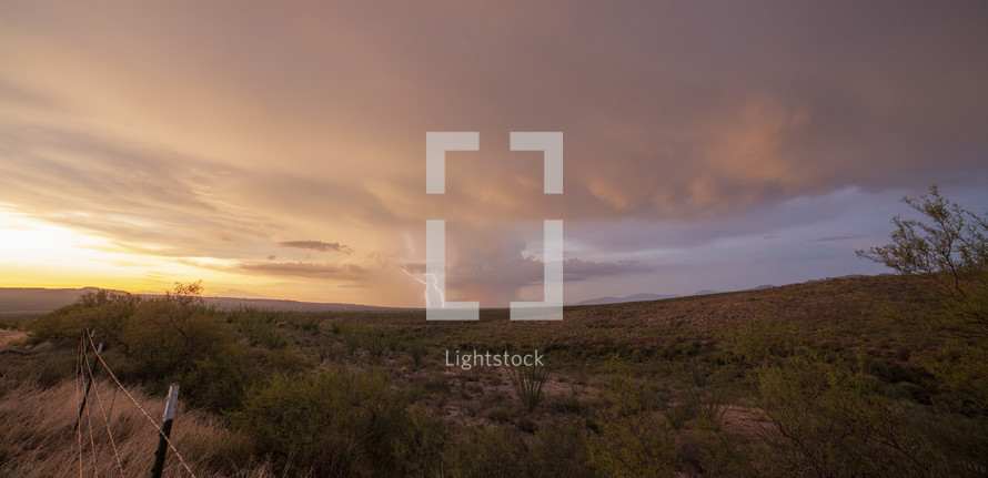 Double lightning strikes on a desert landscape at sunset