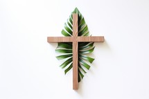 Palm Sunday. Cross made of wood with green palm on the white wall background.