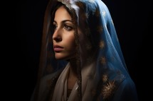 Portrait of Mother Mary in a blue veil over dark background