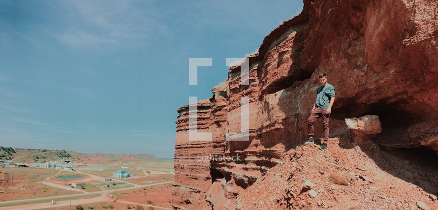 man standing at the edge of a red rock cliffs