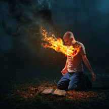 a man on fire kneeling in front of a Bible 