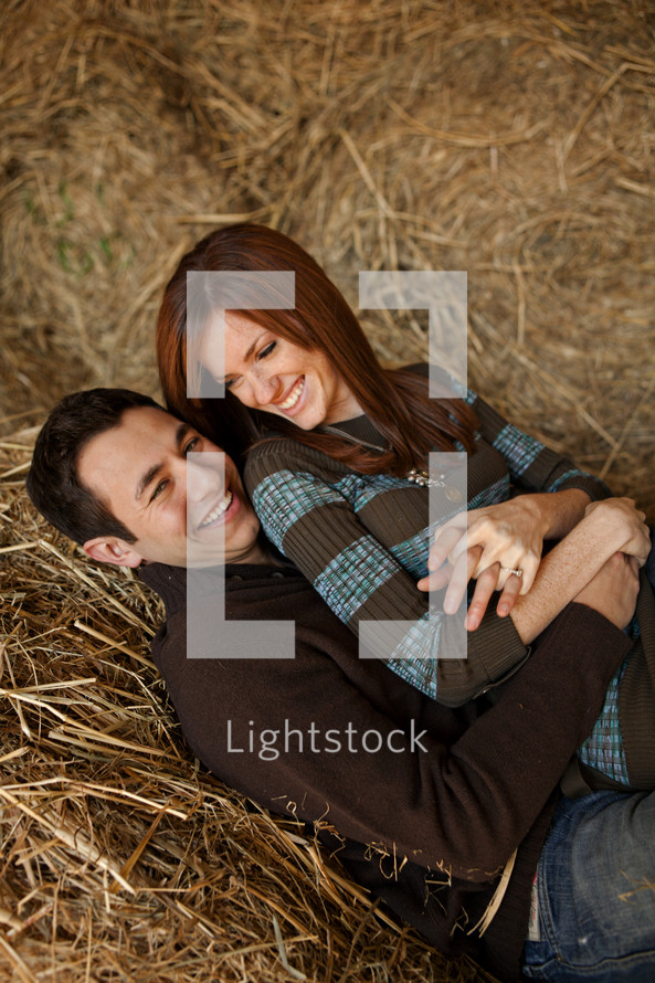 couple snuggling in a hay stack