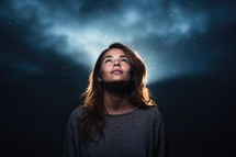 Young woman looking up in the night sky with stars in the background