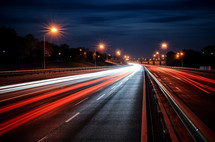 Blurred streaks of red and white lights on a highway from the headlights of moving cars