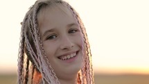 Portrait of a cute teenage girl with African braids. The child is smiling while looking into the camera.