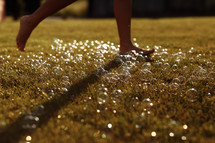 barefoot on a green lawn with soap bubbles.