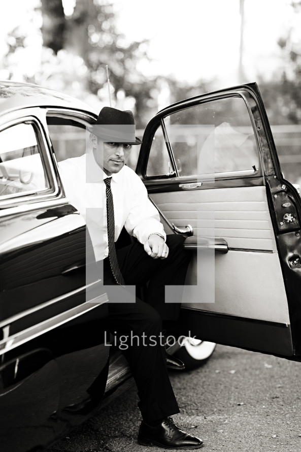 man in a suit and hat getting out of an old car vintage 1950's men
