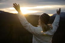 woman with raised arms standing on a mountaintop 