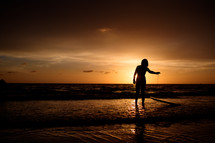 silhouette of a female surfer on a beach at sunset 