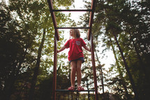 a girl child playing on monkey bars 