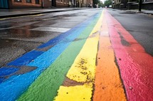 Rainbow drawn on wet city asphalt after rainfall, viewed from a perspective angle