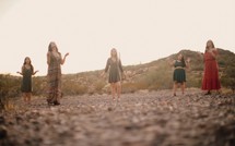 women socially distancing praying in the desert 