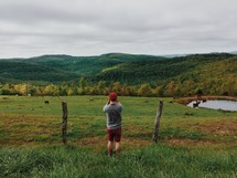 A man photographing cows in a pasture.