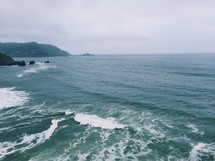 Ocean waves and a hilly seashore.