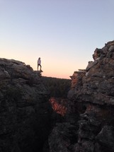 man standing on the edge of a cliff in a canyon