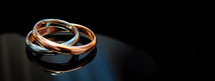 Sacrament: Matrimony. Wedding rings on a black background with reflection and copy space
