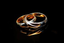 Sacrament: Matrimony. Wedding rings on a black background with reflection, close-up