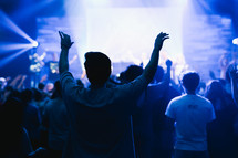 a man standing with raised hands and worship leaders leading a congregation in song 