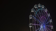 Time lapse of ferris wheel illuminated at night with long exposure and isolated on black sky