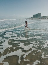 girl child running into the ocean 