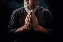 Senior man praying with hands clasped together on black background