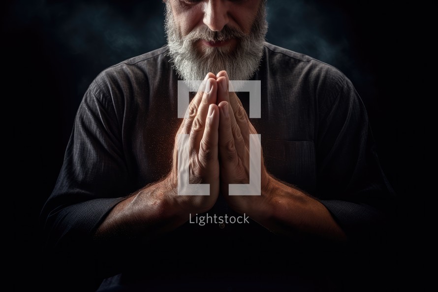 Senior man praying with hands clasped together on black background