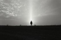 Silhouette of a man standing in the middle of the field.