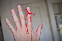 A red string is tied to a figure to remind the person of something.