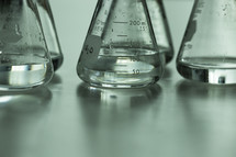 Clear liquid measured in glass scientific measuring flasks.